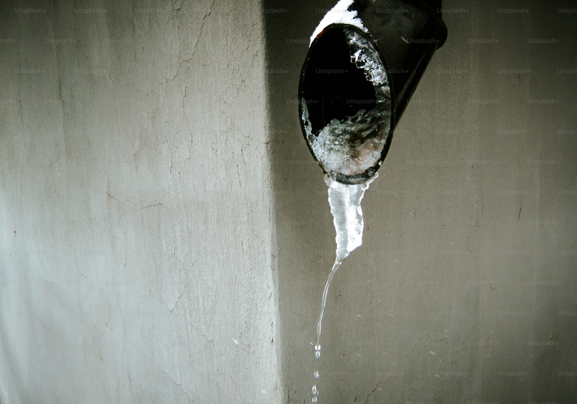 Water leaking from a failed pipe onto the wall below