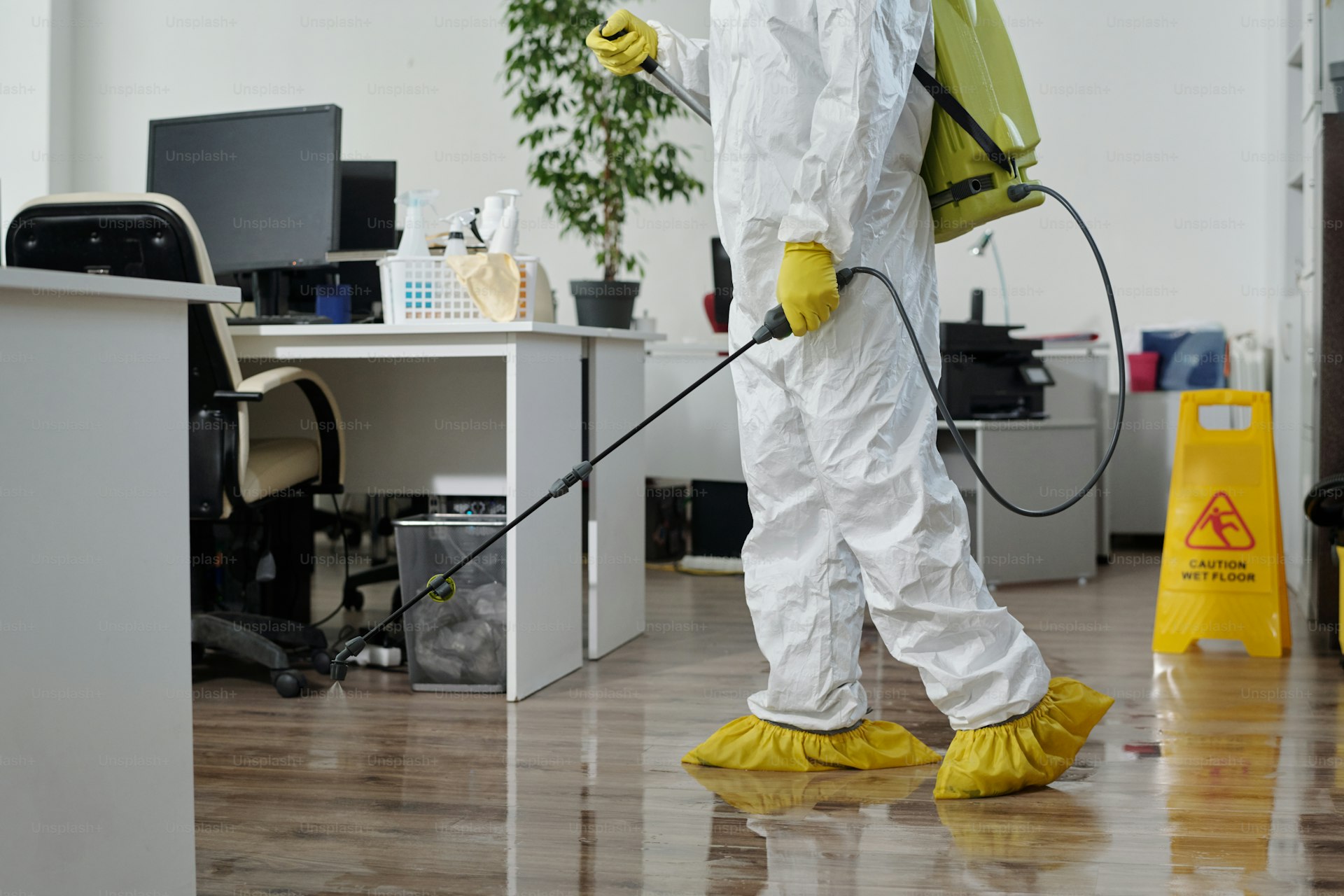 Technician in protective equipment treating a commercial office space